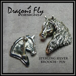 May include: Sterling silver horse head brooch pin. The pin is shown from both the front and back. The back shows the pin mechanism.