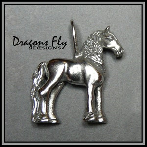 May include: Silver horse charm pendant with a detailed design. The charm is standing on all four legs with its head turned to the side. The charm is made by Dragons Fly Designs.