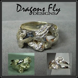 May include: Silver ring featuring a detailed sculpted horse design. The horse is depicted in mid-stride, with its mane and tail flowing behind it. The ring is a double band, with the horse design on the top band.