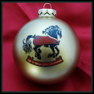 May include: Gold Christmas ornament with a black horse wearing a red blanket and the text "All I Want For Christmas".