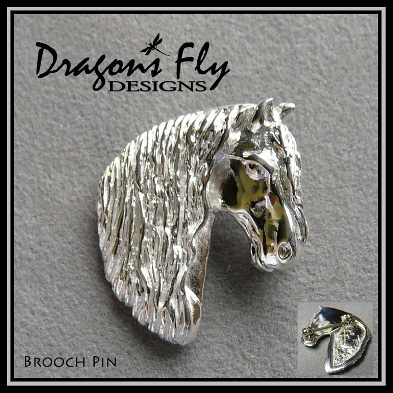 Op de afbeelding: Zilveren broche in de vorm van een paardenkop met een getextureerde afwerking. De broche is een gedetailleerde weergave van een paardenkop met een manen en een getextureerd oppervlak. De broche is bevestigd aan een zilveren achterkant met een pin.