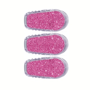 May include: Three pink glitter adhesive covers for a medical device. The covers are clear and have a pink glitter design.