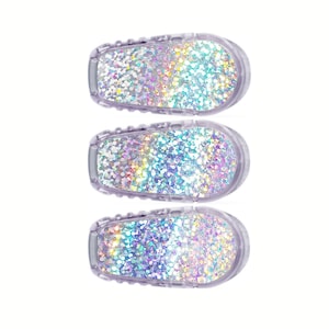 May include: Three iridescent glitter insulin pump covers. The covers are a light purple color with a holographic glitter design.