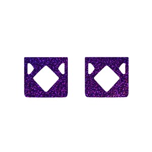 May include: Two purple glitter squares with a white diamond shape in the center.