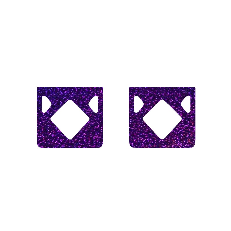 May include: Two purple glitter squares with a white diamond shape in the center.