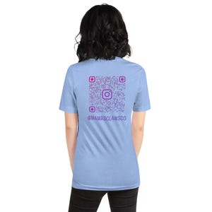 May include: A light blue short-sleeved t-shirt featuring a purple QR code printed on the back. The QR code includes a central Instagram logo icon and the text @MAMASCLAWSCO printed in purple directly underneath the graphic design.