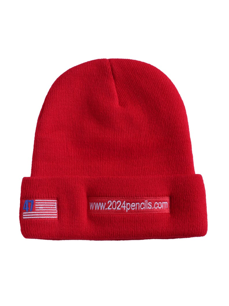 May include: Red knit beanie with a white embroidered American flag and the text "www.2024pencils.com" on the front.