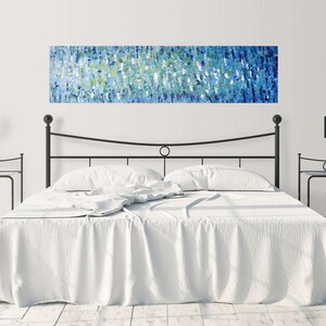 May include: A white bed with a black metal frame and headboard. The bed has a white duvet and two white pillows. There is a blue and green abstract painting hanging above the headboard.