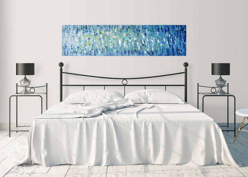 May include: A white bed with a black metal frame and headboard. The bed has a white duvet and two white pillows. There is a blue and green abstract painting hanging above the headboard.