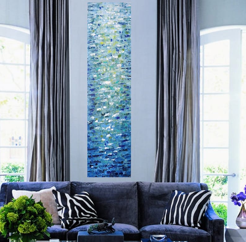 May include: Abstract painting with a vertical design of blue, green, and white paint. The painting is displayed on a wall in a living room setting.
