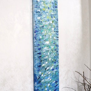 May include: Abstract painting on canvas with a vertical orientation. The painting features a blue, green, and white color scheme with a textured, brushstroke effect. The painting is mounted on a white wall.