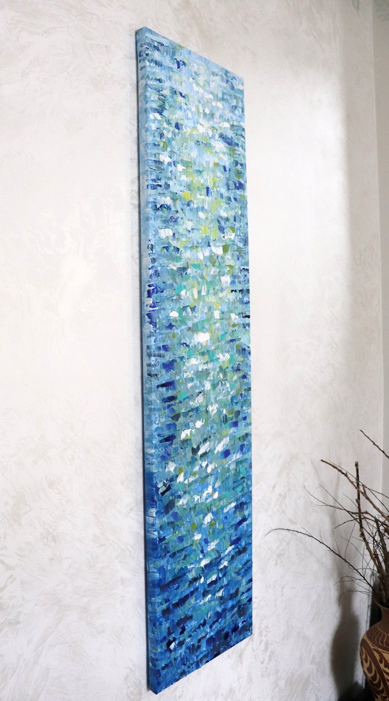 May include: Abstract painting on canvas with a vertical orientation. The painting features a blue, green, and white color scheme with a textured, brushstroke effect. The painting is mounted on a white wall.