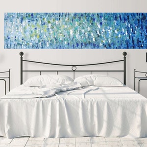May include: A white bed with a black metal headboard and two black nightstands with lamps. A large abstract painting in shades of blue, green, and white hangs above the headboard.
