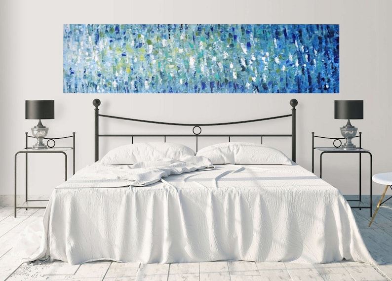 May include: A white bed with a black metal headboard and two black nightstands with lamps. A large abstract painting in shades of blue, green, and white hangs above the headboard.