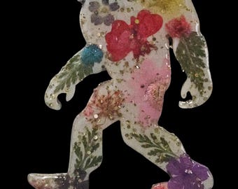 Bigfoot/Sasquatch wooden magnet with dried flowers and glitter 4 inches long. Each one is unique and may differ from one shown