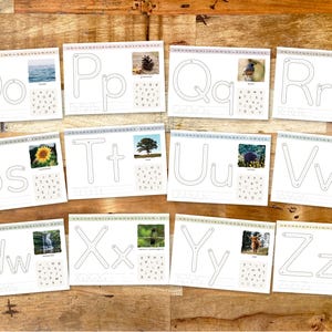 May include: A collection of white cards with the letters O, P, Q, R, S, T, U, V, W, X, Y, and Z. Each card features a large letter outline, a small letter outline, and a corresponding image. The cards are arranged on a wooden surface.