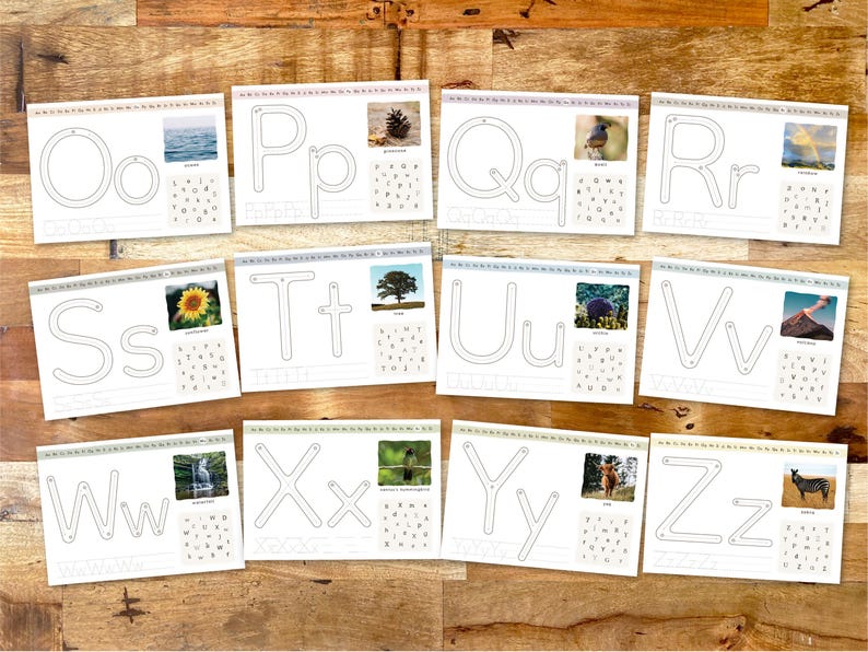 May include: A collection of white cards with the letters O, P, Q, R, S, T, U, V, W, X, Y, and Z. Each card features a large letter outline, a small letter outline, and a corresponding image. The cards are arranged on a wooden surface.