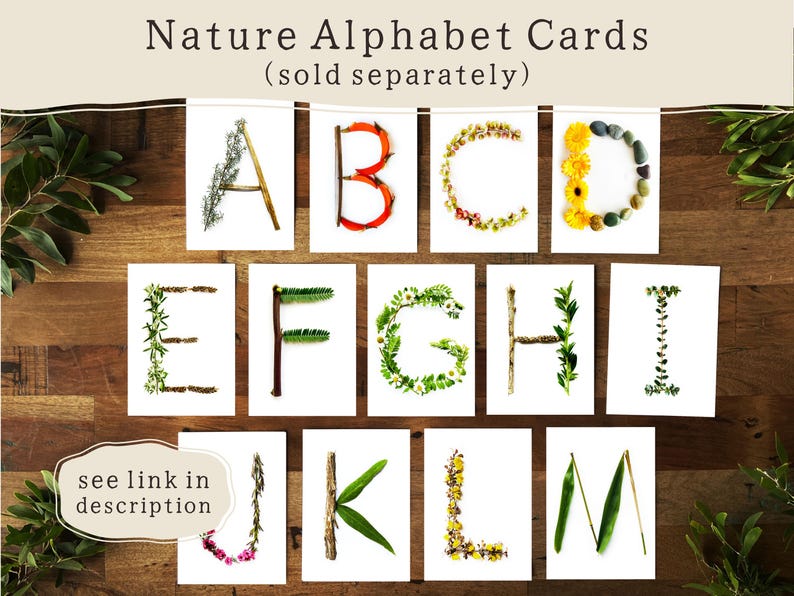 May include: Nature Alphabet Cards featuring letters A through M, each crafted from natural elements like flowers, leaves, and twigs. The cards are displayed on a wooden surface, with the text "Nature Alphabet Cards" and "(sold separately)" at the top.