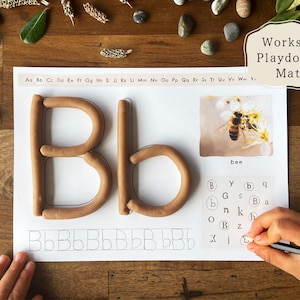 May include: A learning activity mat with the letter "Bb" formed from brown playdough. The mat includes a picture of a bee, the word "bee", and letter tracing exercises. The text "Works as Playdough Mats" is also visible.