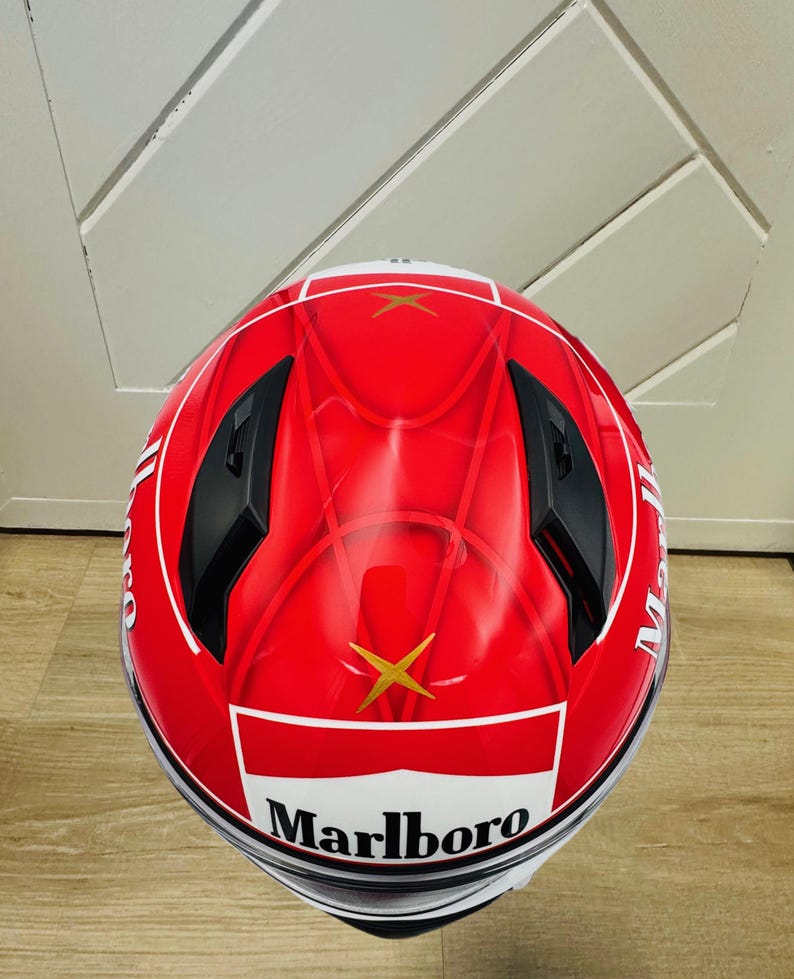 May include: A red motorcycle helmet with a white and gold Marlboro logo. The helmet has a black visor and black accents.