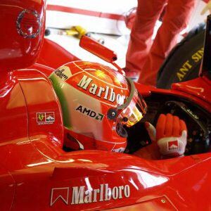 May include: A red race car with a driver wearing a red and white helmet with the word "Marlboro" on it. The car has a large "Marlboro" logo on the side.