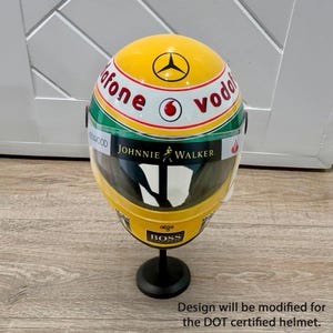 May include: A yellow and black racing helmet with the words "Vodafone" and "Johnnie Walker" visible. The helmet has a clear visor and is mounted on a black stand. The design will be modified for the DOT certified helmet.