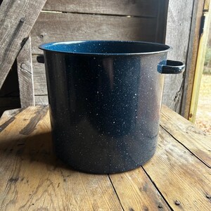 May include: A large, blue enamel pot with white speckles. The pot has two handles on the sides.