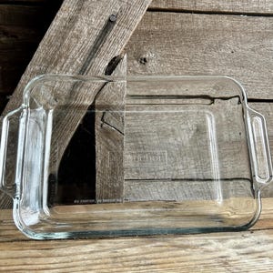 May include: A clear glass baking dish with two handles. The dish is labeled "The Home Kitchen" and has the dimensions 9" x 13".