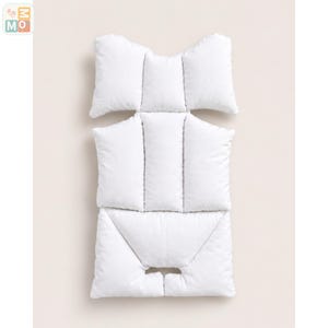 May include: A white padded infant car seat insert featuring a multi-section design with a head support area, a central torso section, and a bottom portion with a cutout for harness straps, providing a soft and cushioned surface for a car seat.
