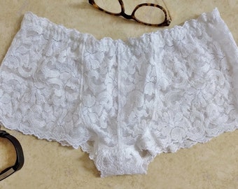May include: White lace underwear with a delicate floral pattern. The underwear has a wide elastic waistband and a scalloped edge.