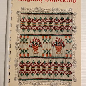 May include: A vintage book titled "English Smocking" with a cream-colored cover. The cover features a detailed illustration of smocked patterns in red, green, and orange, with two flower baskets. The author's name, Grace L. Knott, is at the bottom.