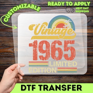 May include: A DTF transfer with a vintage design. The design features the words "Vintage 1965 Limited Edition" in orange and yellow, with a rainbow and palm tree graphic. The transfer is ready to apply and customizable.