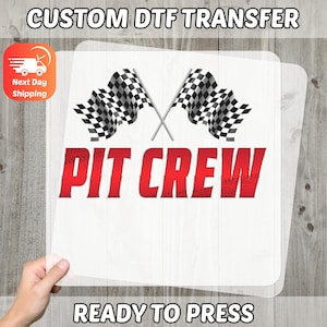 May include: White DTF transfer featuring the words "PIT CREW" in red, and two crossed checkered flags. The text "CUSTOM DTF TRANSFER" and "READY TO PRESS" are also visible.