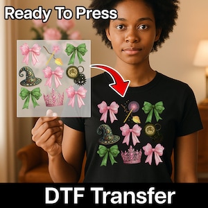May include: A black t-shirt featuring a DTF transfer design with pink bows, a witch hat, a crown, and green bows. The words "Ready To Press" and "DTF Transfer" are displayed in the image.