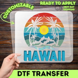 May include: A DTF transfer featuring a colorful Hawaiian sunset design with palm trees, mountains, and the word "HAWAII" in blue. The transfer is labeled "CUSTOMIZABLE" and "READY TO APPLY".