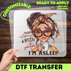 May include: A DTF transfer sheet featuring a cartoon illustration of a person with dark hair in a messy bun, wearing a patterned headscarf and glasses, holding a white mug. The text reads: I'M NOT always A BITCH sometimes I'M ASLEEP.