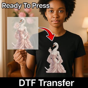 May include: A black t-shirt featuring a graphic print of a white swan with a long neck wearing a pale pink satin dress and holding a small perfume bottle. The text Ready To Press and DTF Transfer is visible on the image along with a red arrow.