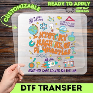 May include: A clear DTF transfer sheet featuring a vibrant science-themed design. The design includes the text "MYSTERY MACHINE OF DIAGNOSTICS" and various lab-related illustrations. The words "CUSTOMIZABLE" and "READY TO APPLY" are also visible.