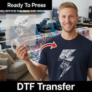 May include: A DTF transfer sheet featuring a white lightning bolt graphic filled with a desert landscape illustration, including a cactus and rock formations. The same graphic is shown applied to a dark navy blue t-shirt. Text reads Ready To Press.