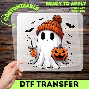May include: A DTF transfer with a cartoon ghost wearing an orange beanie, holding a drink and a jack-o'-lantern. The ghost is surrounded by bats and stars. The transfer is labelled "Customizable" and "Ready to Apply".