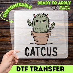 May include: A DTF transfer featuring a cartoon cactus with cat ears in a brown pot. The word "CATCUS" is below the cactus. The transfer is labelled "CUSTOMIZABLE" and "READY TO APPLY".