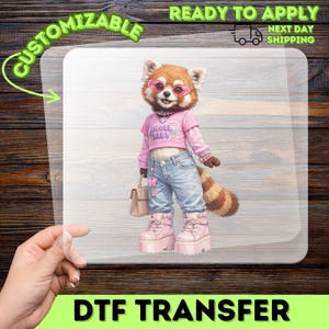 May include: A DTF transfer sheet featuring a red panda character wearing pink sunglasses, a pink crop top with the text ANGEL BABY, light blue jeans with a butterfly charm, and pink platform boots, while holding a small beige handbag.