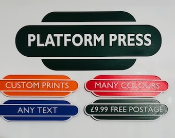 May include: A white background with the words "PLATFORM PRESS" in white on a dark green oval. Below are four colored ovals with the text "CUSTOM PRINTS", "MANY COLOURS", "ANY TEXT", and "FREE POSTAGE".