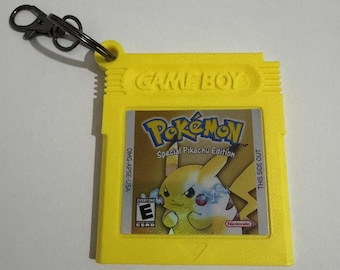 Puede incluir: Llavero de cartucho de Game Boy amarillo con el juego Pokémon Special Pikachu Edition. El cartucho tiene el texto "GAME BOY" en relieve. La etiqueta del juego muestra a Pikachu y el logotipo de Nintendo. Incluye un cierre metálico.