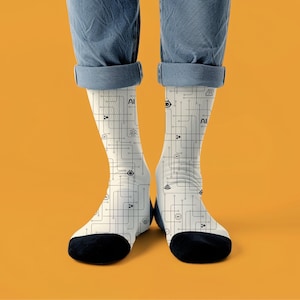 Może przedstawiać: Para skarpetek z białym tłem i czarnym wzorem płytki drukowanej. Skarpetki mają czarne pięty i palce, a na nich wydrukowano słowo "AI". Skarpetki są noszone z niebieskimi dżinsami.