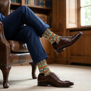 May include: A person seated in a leather armchair, wearing navy blue trousers and brown leather dress shoes. The socks feature a geometric pattern in shades of teal, yellow, red, and brown. The background includes a bookshelf and a window.