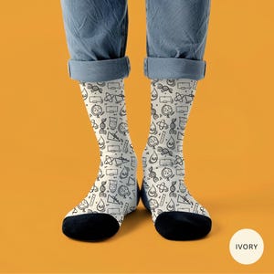 Könnte beinhalten: Elfenbeinfarbene Socken mit einem schwarzen, wissenschaftlichen Muster. Die Socken zeigen Illustrationen von Bechern, DNA-Strängen und anderen wissenschaftlichen Symbolen. Die Socken haben schwarze Fersen und Zehen.