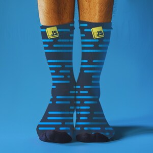 May include: Navy blue socks with a pattern of light blue horizontal lines. Each sock features a yellow square with the letters "JS" on the cuff. The socks are set against a solid blue backdrop.