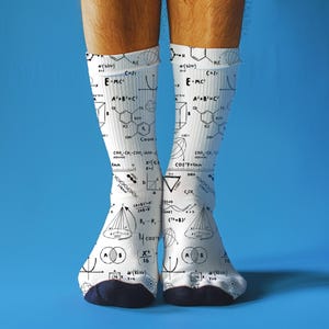 Könnte beinhalten: Weiße Socken mit marineblauer Spitze und Ferse, bedeckt mit schwarzen wissenschaftlichen Formeln und Diagrammen. Die Socken zeigen Gleichungen, chemische Strukturen und mathematische Symbole. Kniehohe Socken.