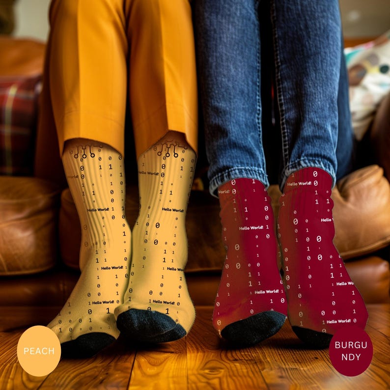 May include: Peach-colored and burgundy socks with a binary code pattern and the text "Hello World!" are displayed. The socks are worn by two people, with one pair in peach and the other in burgundy.